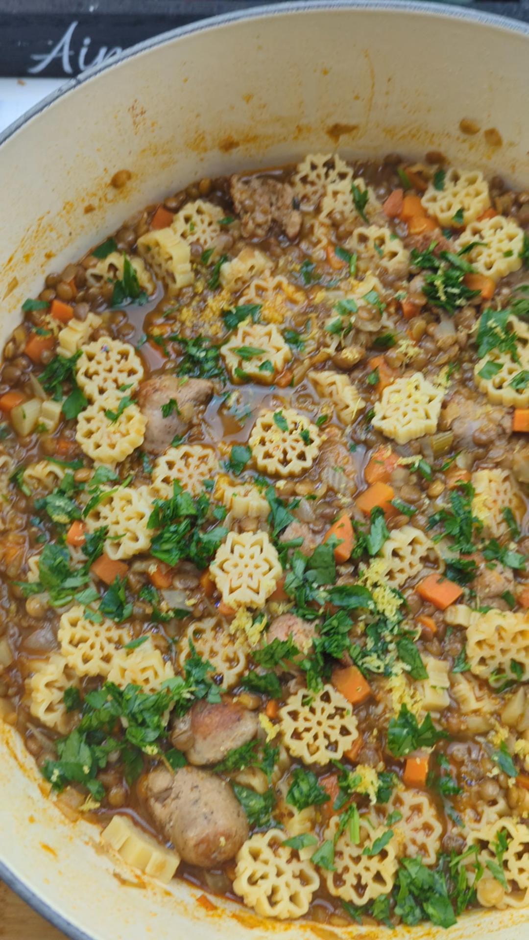 A comforting bowl of winter lentil and sausage stew topped with grated parmesan cheese and served next to optional chili oil.