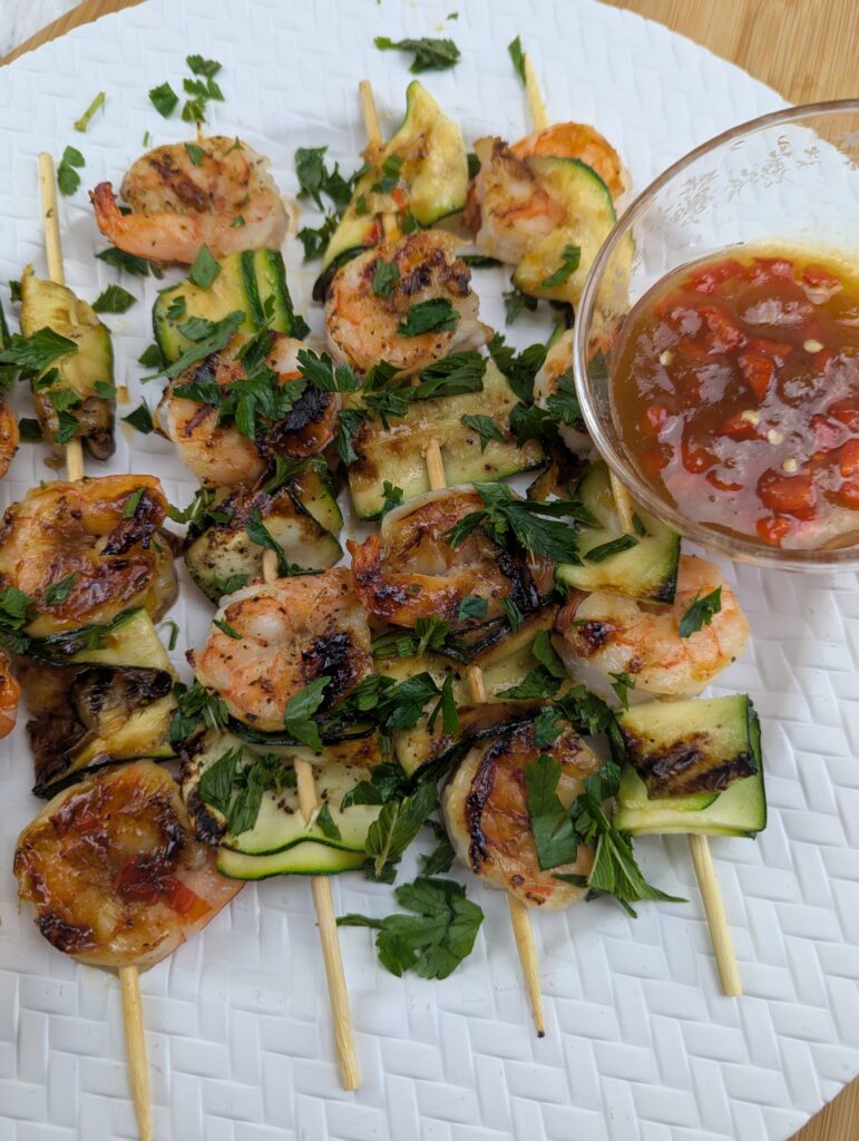 Sweet and spicy apricot shrimp skewers with grilled zucchini ribbons and fresh mint on a hot grill pan.