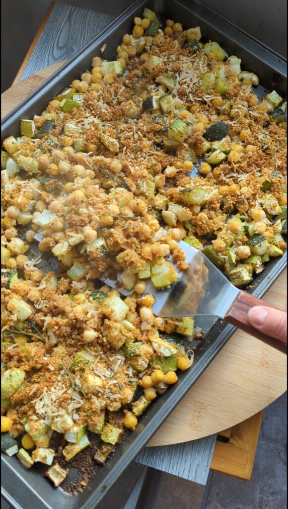 Overhead shot of diced zucchini on tray baked with chickpeas until the chickpeas are crispy and brown. Topped with a bread and parmesan vrunchy topping