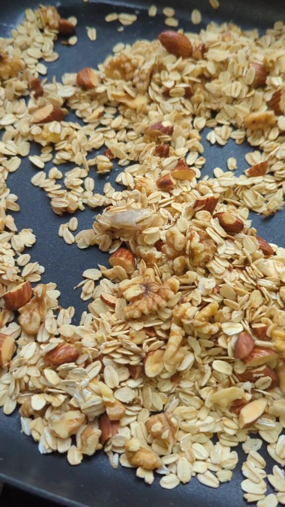 Rolled oats, walnuts and almonds toasting in coconut oil in a skillet.