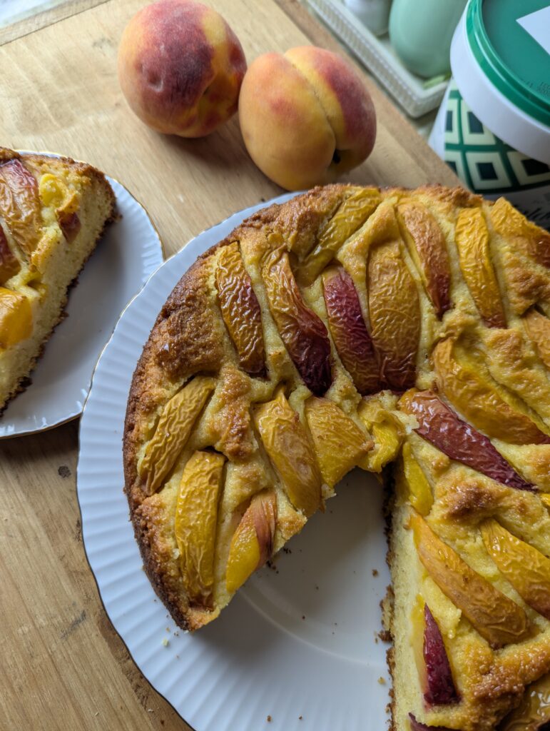 Golden peach polenta cake topped with fresh Ontario peach slices on a rustic wooden board.