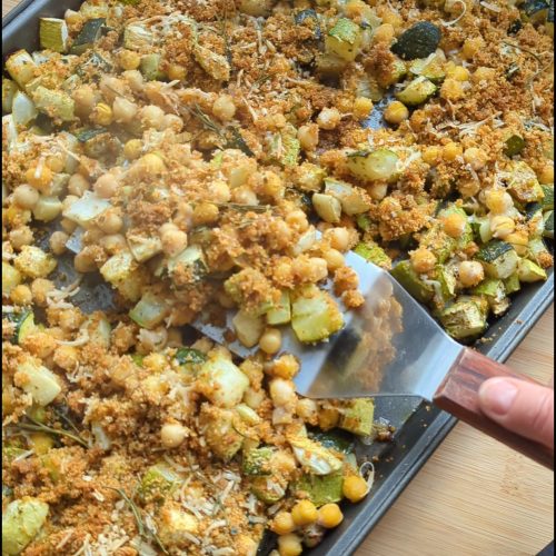 Overhead shot of diced zucchini on tray baked with chickpeas until the chickpeas are crispy and brown. Topped with a bread and parmesan vrunchy topping